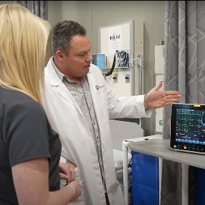 A student watches as a medical instructor demonstrates the use of a piece of equipment.